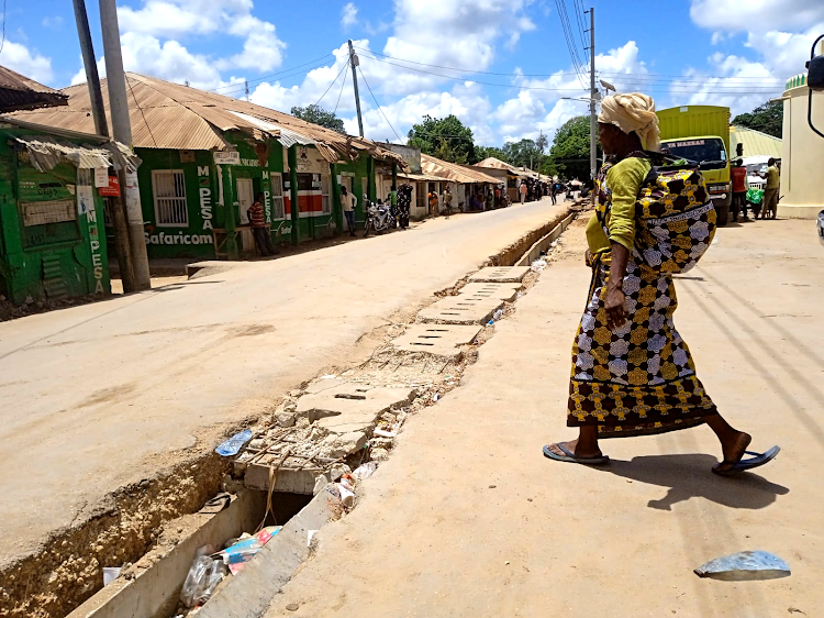 A woman walks across an incomplete section of the road in Witu town.