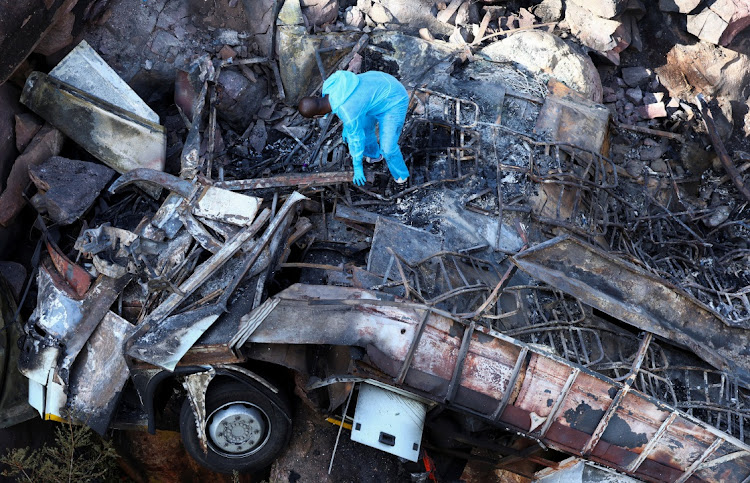 A forensic pathologist combs the burnt remains of the bus that was taking Easter pilgrims from Botswana to Moria, after it crashed near Mamatlakala, Limpopo, March 29 2024. Picture: REUTERS/Siphiwe Sibeko