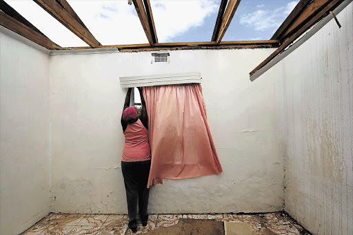 STORM DAMAGE: A neighbour removes curtains for Nellie and Jacobus Windvogel, who lost their roof during a freak storm that hit Barrydale in Western Cape on Monday afternoon. About 40 homes were affected in the nearby Smitsville area, officials said.
