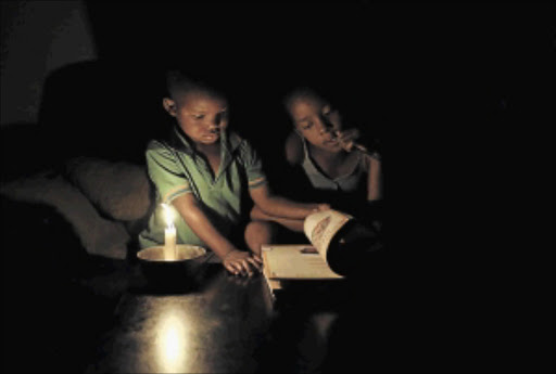 Sinovuyo Bhungane, right, is interrupted by her cousin Yonga as she studies using candle light during load-shedding in Soweto this week. Eskom will implement rolling blackouts all of this week, the company said on its official Twitter account Photo: Siphiwe Sibeko/REUTERS