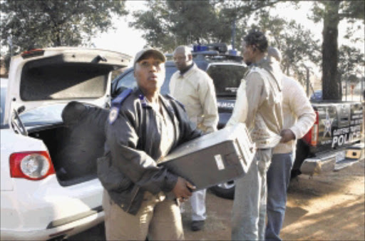 EVIDENCE: Members of the commercial crimes unit confiscate two computers suspected of having been used in the printing and selling of counterfeit World Cup accreditation cards.Pic. MOHAU MOFOKENG. 18/06/2010. © Sowetan.
