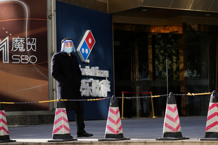 A security guard wearing a face mask and a face shield stands near an office building, as Covid-19 outbreaks continue in Shanghai, China, on December 14 2022. Picture: REUTERS/ALY SONG