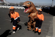 A person in a dinosaur costume plays around at Comic Con Africa 2018.