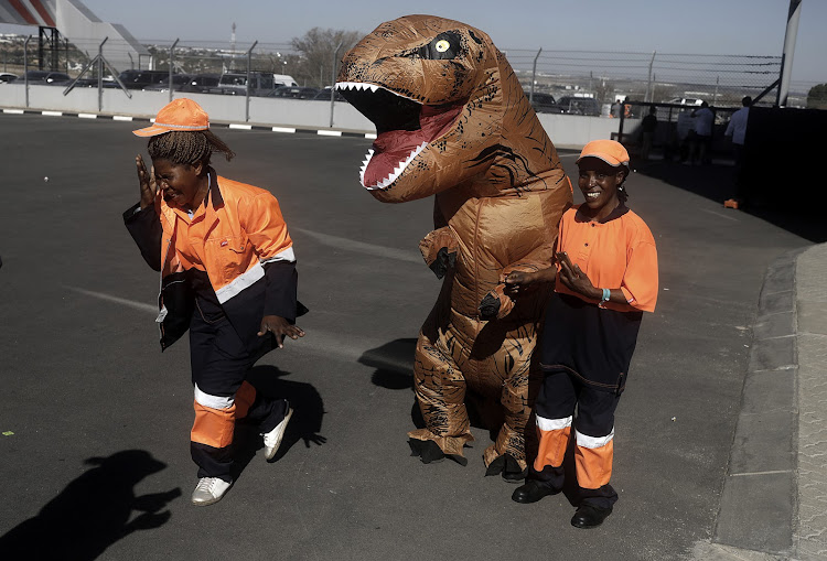A person in a dinosaur costume plays around at Comic Con Africa 2018.