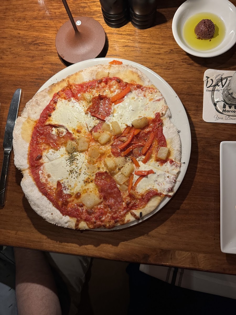 Gluten free pizza with mozzarella, spicy salami, red peppers, and red sauce.