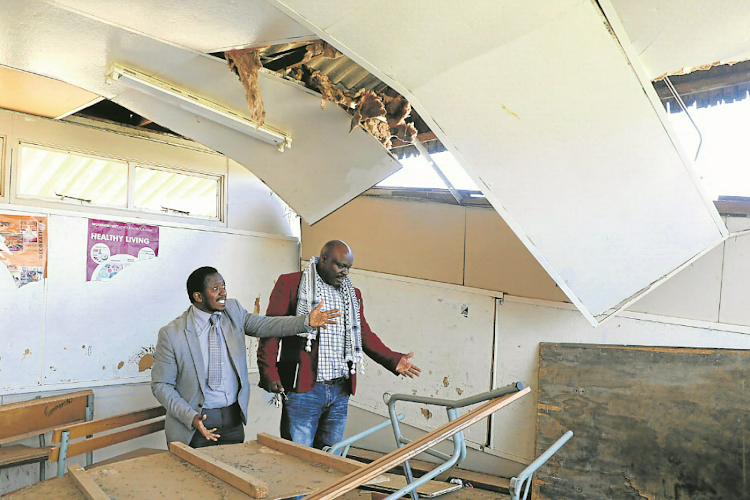 Schornville Primary SGB members Mzwandile Vaaiboom and Zendzile Aries point at some of the damage at the school.