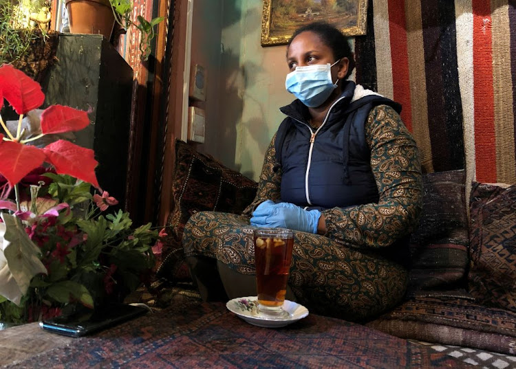 A woman wears a mask and gloves at a restaurant in Cape Town, on March 20 2020, as a measure to combat the spread of the coronavirus.