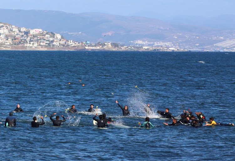 Local surfers throw flowers during a demonstration calling for authorities to solve the disappearances of US and Australian surfers in Ensenada after Mexican authorities said the parents of the missing tourists arrived in Mexico to try to identify the dead bodies believed to be their children, in Ensenada, Mexico, on May 5 2024.