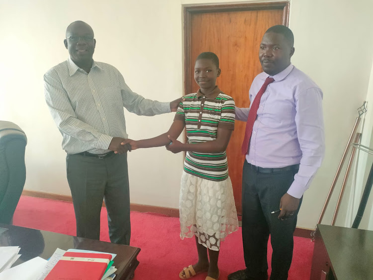 The Education CEC John Awiti (specs) and the 14-year-old girl accompanied by Acting Chief Officer for Education, Daniel Okuta in Kisumu.