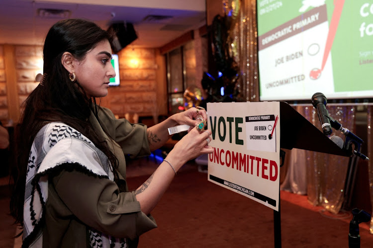 Activist Natalia Latif tapes a Vote Uncommitted sign on the speaker's podium during an uncommitted vote election night gathering as Democrats and Republicans hold their Michigan primary presidential election, in Dearborn, Michigan, US, on February 27 2024. Picture: REBECCA COOK/REUTERS