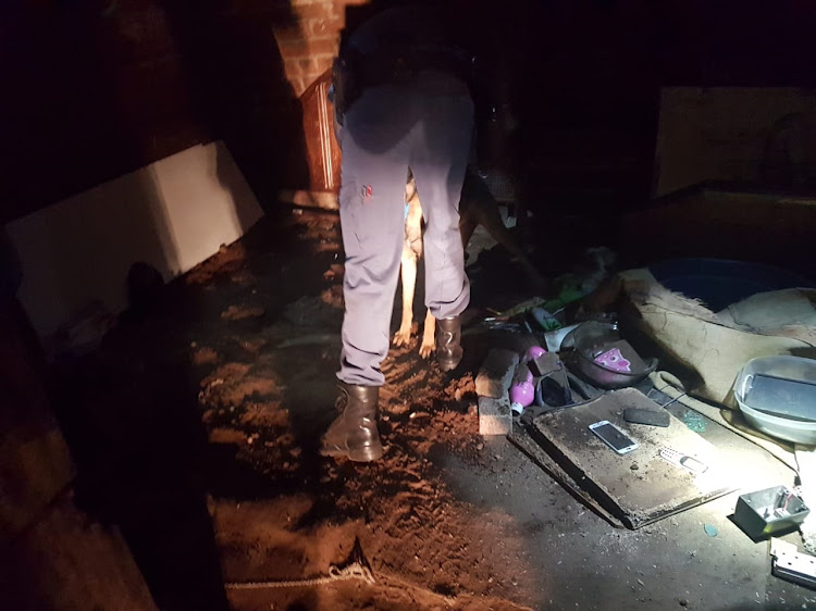Police combing the scene inside a shack in Jeppe, Johannesburg, where two bodies were found in a shallow grave.