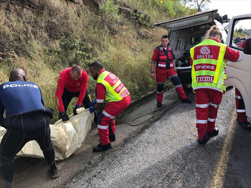 Police search and rescue officers retrieve the body of Pius Shange, who drowned in a drain in south Durban, in heavy rains at the weekend PICTURE: JACKIE CLAUSEN