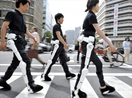 Japan's robotics venture Cyberdyne employees wearing the robot-suit "HAL" (Hybrid Assistive Limb) as they walk on a street in Tokyo for a demonstration.