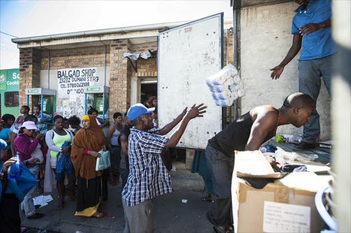 Community members help to clear out a Somali owned shop’s store room on April 18 2016 after violent protests on Sunday night in Dunoon left foreign shop owners devastated.