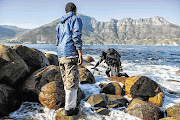 STEALTH MISSION: A diver leaves the sea along the Hout Bay coastline after poaching for perlemoen as a minder waits to assist him with his haul-bag and gear. Minders earn a little income from the catch