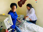 Limpopo MEC for health Dr Phophi Ramathuba and a member of staff at an undisclosed hospital attending to the eight-year-old sole survivor of the bus accident.