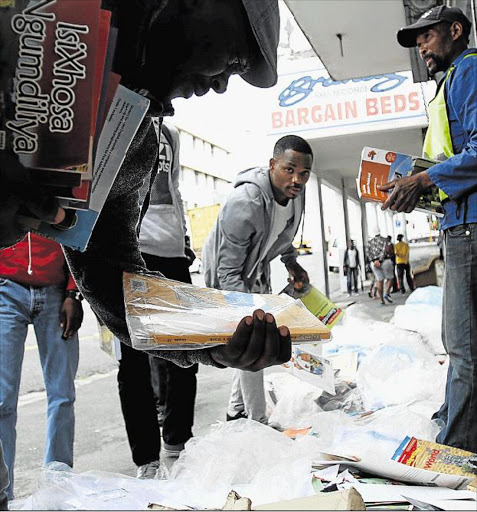 WHAT A WASTE: Passers-by in the CBD rummage through hundreds of school textbooks to save them from being ripped up page by page by three men who said they had been asked to tear them up for recycling Picture: SIBONGILE NGALWA