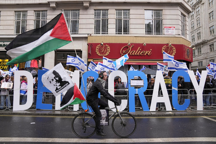 A man rides a bike with Palestinian flags next to demonstrators with Israeli flags during a protest against Israeli Prime Minister Benjamin Netanyahu as he visits Britain, in London, Britain March 24, 2023.
