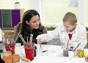 Catherine, Duchess of Cambridge watches Luis Lee, 8, paint during a visit to The Art Room facilities at Rose Hill Primary School in Oxford, southern England, yesterday. The duchess is patron of The Art Room