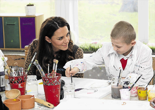 Catherine, Duchess of Cambridge watches Luis Lee, 8, paint during a visit to The Art Room facilities at Rose Hill Primary School in Oxford, southern England, yesterday. The duchess is patron of The Art Room