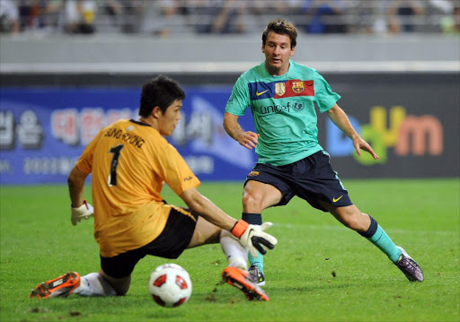 Spain's Primera Liga champion FC Barcelona's Argentinian player Lionel Messi (R) shoots the ball as South Korea's all-star football team goalkeeper Jung Sung-Ryong (L) tries to block during an exhibition match in Seoul on August 4, 2010.