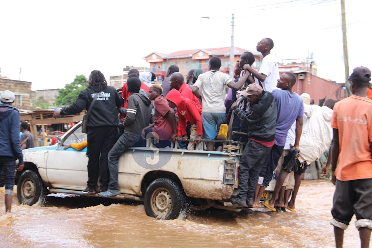 Locals take a ride on a pickup to cross a flooded road at a bridge connecting Mwiki and Kasarani on April 24, 2024.