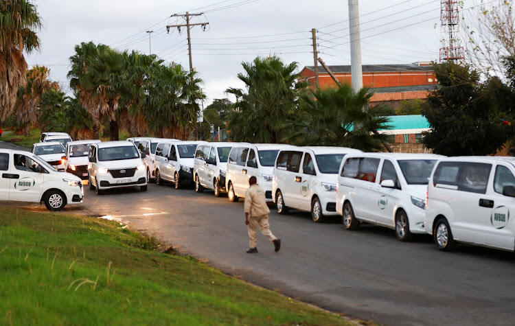 A man passes mortuary vans loaded with empty coffins at a funeral parlour ahead of the mass funeral.