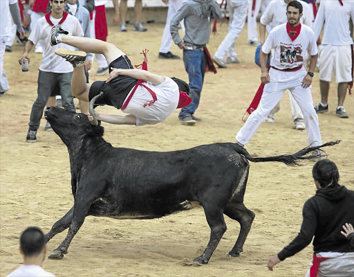 UP AND OVER: Another reveller bites the dust during the running-of-the-bulls festival in Pamplona, northern Spain, yesterday. The annual nine-day testosterone-fuelled event honours St Fermin, Pamplona's patron saint