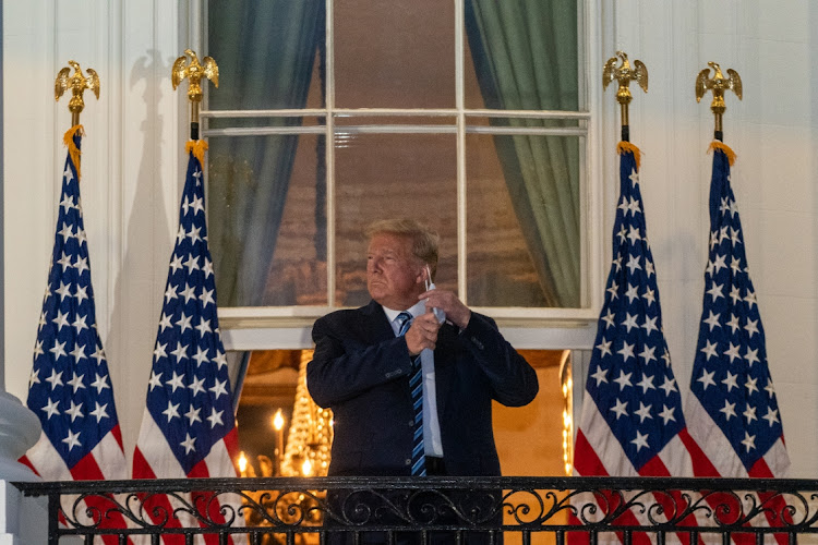 U.S. President Donald Trump removes his protective mask on the Truman Balcony of the White House in Washington, D.C., U.S., on Monday, Oct. 5, 2020.