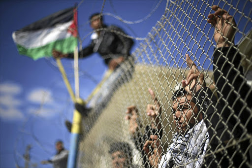 Palestinians stand behind a fence as they wait for the arrival of their relatives at Rafah crossing after it was opened by Egyptian authorities to allow stranded Palestinians to return to Gaza.