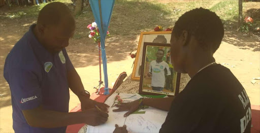 Thika United coach Gabriel Njoroge signs Dennis Lewa's football jersey during the funeral in Tsagwa, Kaloleni constituency on Saturday, October 20, 2018 / BRIAN OTIENO