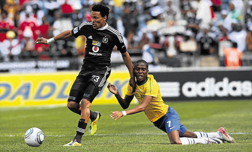 Tlou Segolela of Orlando Pirates slips through an attempted tackle by Elias Pelembe of Mamelodi Sundowns during the MTN8 semi-final first leg played at Orlando Stadium in Soweto yesterday. Pirates won the game 3-2 Picture: SYDNEY SESHIBEDI