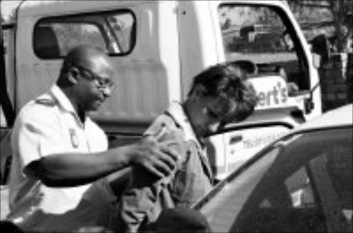 GOTCHA: Captain Leonard Hlathi of the Mpumalanga police organised crime unit escorts Captain Lana Basson to a waiting police car shortly after her arrest on Friday. Pic. Riot Hlatshwayo. 28/05/08. © Sowetan.