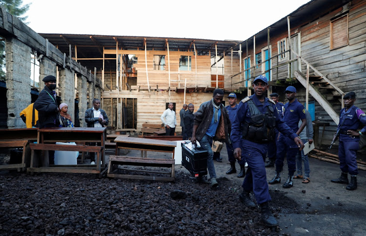 An Independent National Electoral Commission (CENI) agent is escorted by Congolese policemen as they arrange electoral materials at a polling centre on the day of the presidential election in Goma, North Kivu province of the Democratic Republic of Congo on December 20 2023.