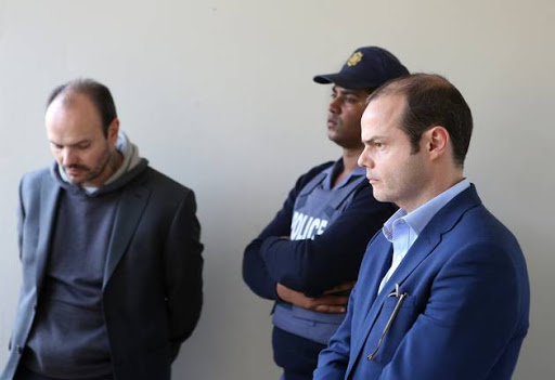 Lucas Dougherty right with his handcuffed brother, Diego Novella, during an inspection of the crime scene at the Camps Bay Retreat Hotel on Tuesday.