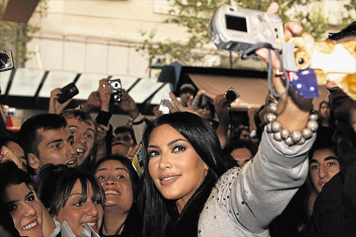 Reality TV star Kim Kardashian photographs herself with fans while they take photos of her. Many of the photos will be posted on social networking sites in a world where privacy has died