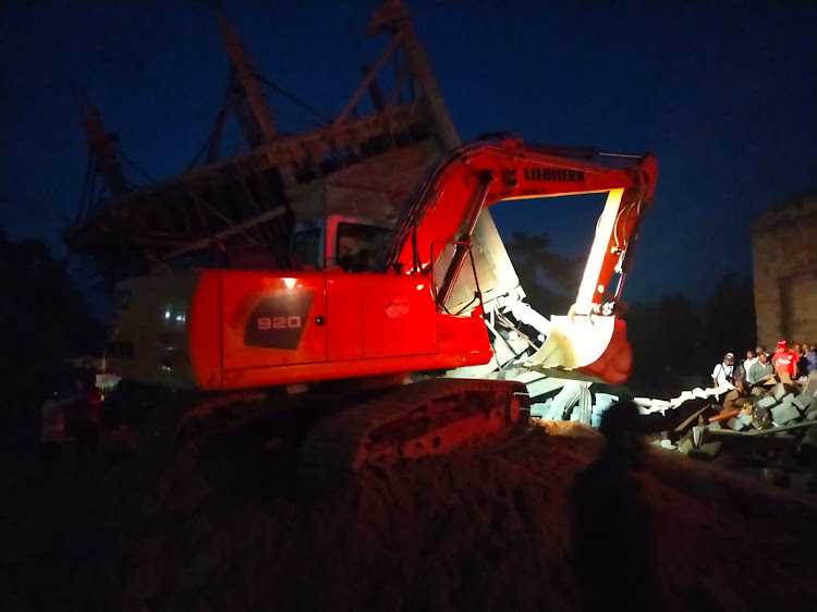 An earth mover moves rubble as rescue operations continue on Monday night following the collapse of a four-storey building in Murang'a, June 19, 2023.