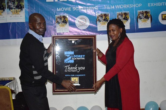 Prof Peter Amuka hands over a present to the Kenya Film Commission /handout