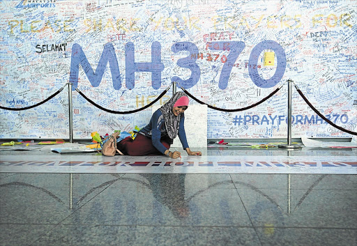HOPEFUL: A woman writes a message on a display at Kuala Lumpur Airport days after the disappearance of Malaysia Airlines flight MH370. File photo