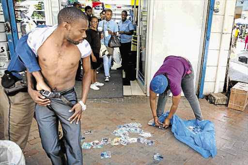 GET A GRIP: A street vendor looks at his wares as he is arrested in central Johannesburg during a raid by the police's commercial crimes unit yesterday. The raid was in response to a tip-off that pornography was being sold on the streets