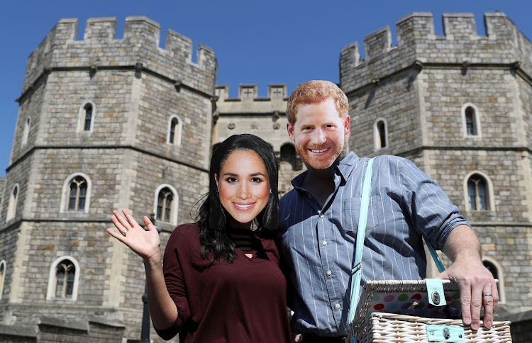 A couple wear Prince Harry and Meghan Markle face masks outside Windsor Castle, in Windsor, Britain, May 15, 2018.