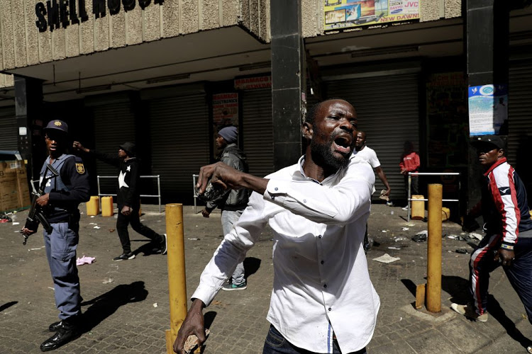 A foreigner reacts in the Johannesburg CBD after the protests erupted and shops were looted. Attacks on foreigners are but one factor in SA's increasingly grim outlook.