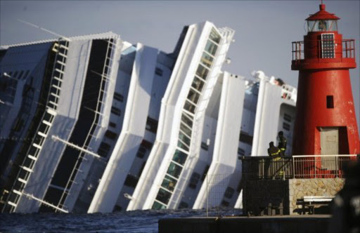 Firemen look at the emerged side of the cruise liner Costa Concordia on January 17, 2012. The Costa Concordia grounded in front of the harbour of Isola del Giglio after hitting underwater rocks on January 13.