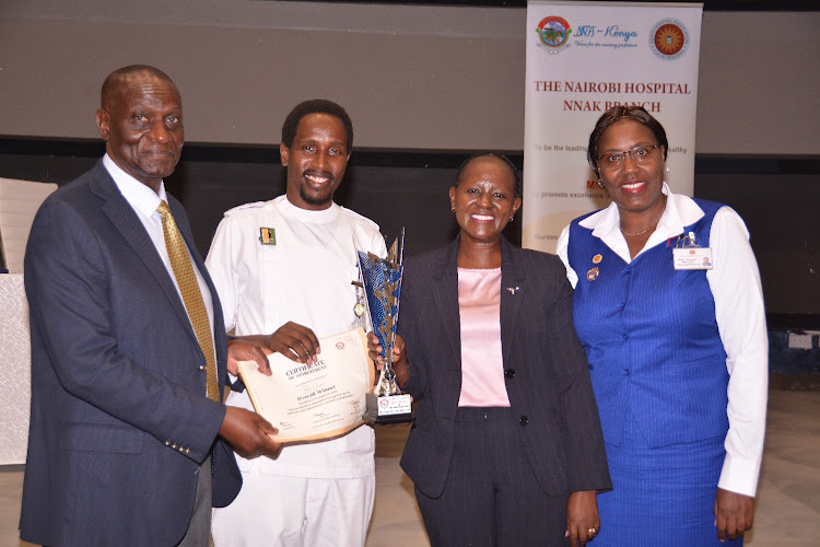 Senior nurse Felix Chumo (2nd left) scoops overall winner's trophy as The Nairobi Hospital celebrates top nurses during the International Nurses Week. On the left is the hospital's CEO James Nyamongo and Director Nursing Services Mary Kamau (right).