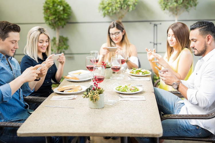People at a lunch table using their smartphones.