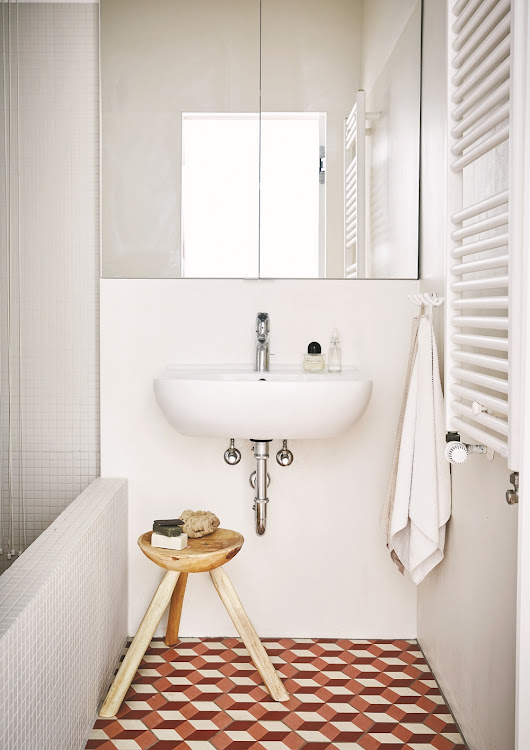 The bathroom is sleek and minimalist; it's tiled with patterned, untreated cement tiles.