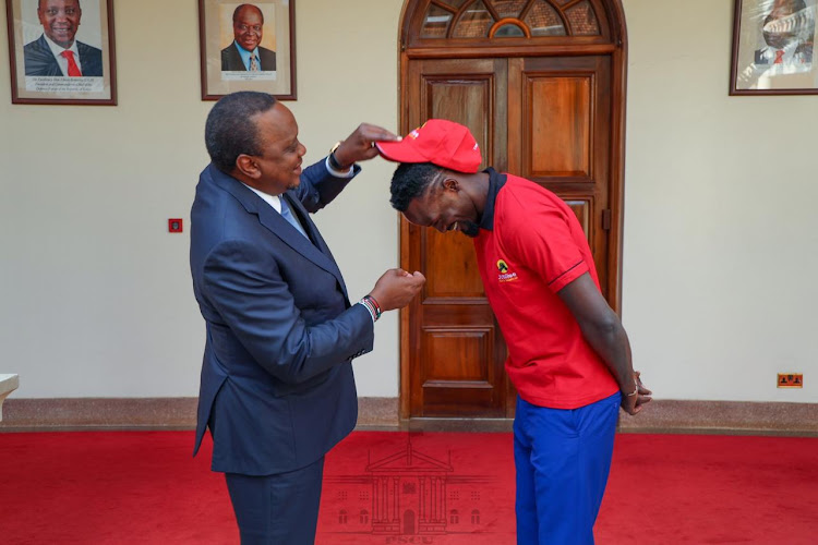 President Uhuru Kenyatta dresses Mariga a Jubilee Party cap at State House