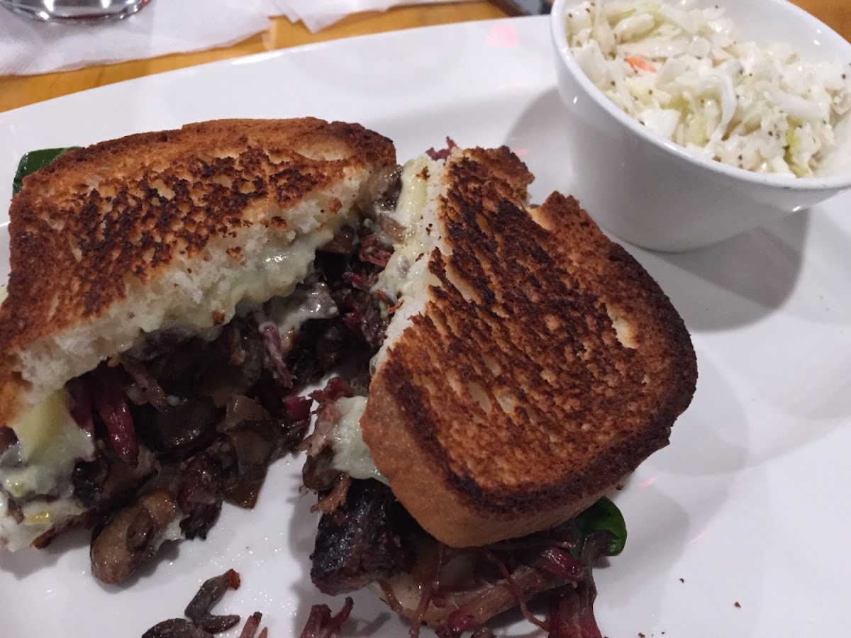 Brisket sandwich on gluten free bread with a side of coleslaw