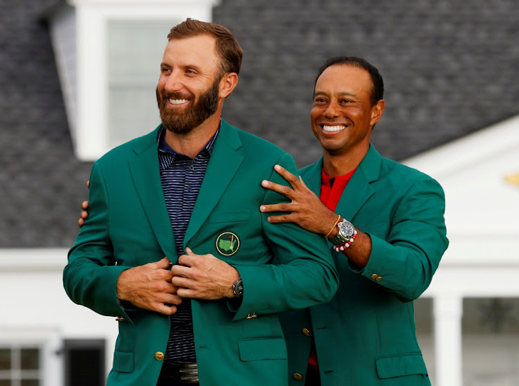 Dustin Johnson of the US is presented with the green jacket by Tiger Woods after winning The Masters at Augusta National Golf Club on November 15, 2020