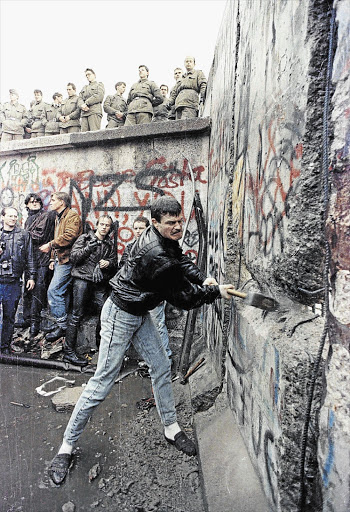 STOP, IT'S HAMMER TIME: A 1989 picture of the demolition of the Berlin Wall while East Berlin border guards watch from above the Brandenburg Gate in Berlin.